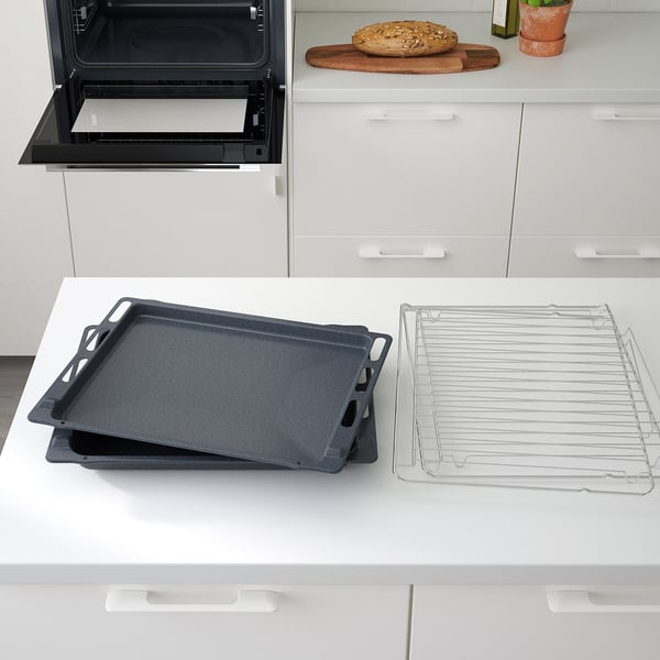 Cuisine moderne avec four autonettoyant ouvert, plaques de cuisson empilées et grille de refroidissement sur le comptoir.
