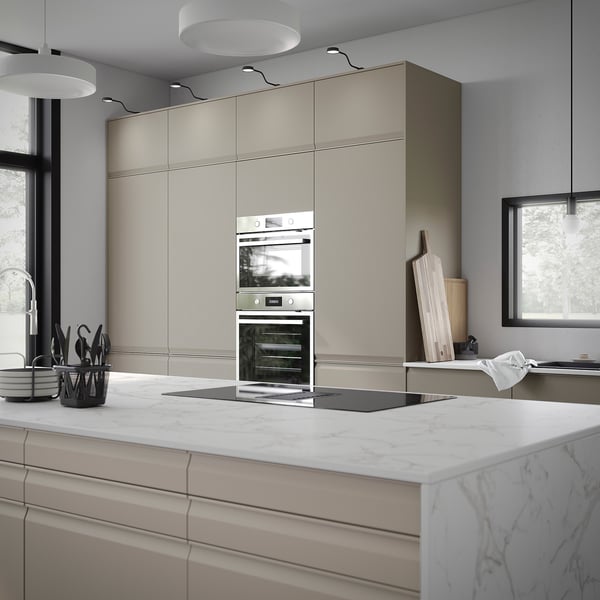 Cuisine moderne avec four en acier inoxydable, armoires beiges, comptoirs en marbre et cuisinière à gaz.