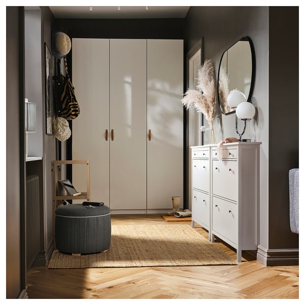 Entrée moderne avec armoire blanche, étagère en miroir, unité de rangement, tapis beige, pouf gris et décor naturel.