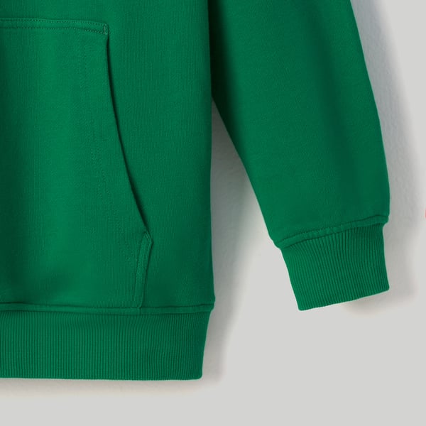 Gros plan sur le sweat à capuche vert vif, montrant une texture de coton doux, une poche kangourou et des poignets et un ourlet côtelés.