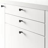 Commode blanche à quatre tiroirs, chacun sécurisé par des boutons noirs, adapté à différentes épaisseurs de porte.