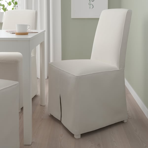 Chaise BERGMUND blanche avec dossier haut, à côté de la table avec tasse et papiers.