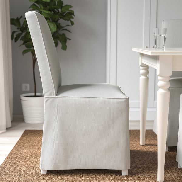 Une chaise rembourrée grise avec un dossier haut et des pieds en bois, adaptée pour s’asseoir confortablement à une table à manger.