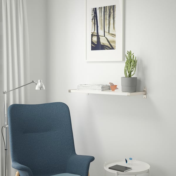 Espace de travail moderne avec chaise de bureau bleue, table ronde et étagère avec plante et art.