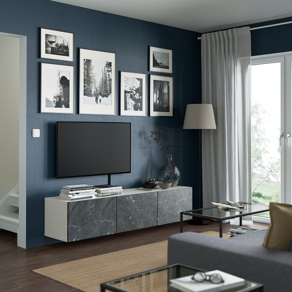 Salon moderne : banc tv BESTÅ avec plateau en marbre, livres, vase. Canapé gris, lampe, table en verre.