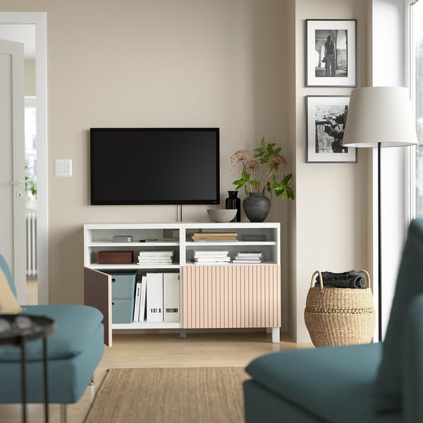 Salon avec canapé bleu sarcelle, télévision à écran plat sur banc TV BESTÅ blanc avec rangement ouvert et plantes.