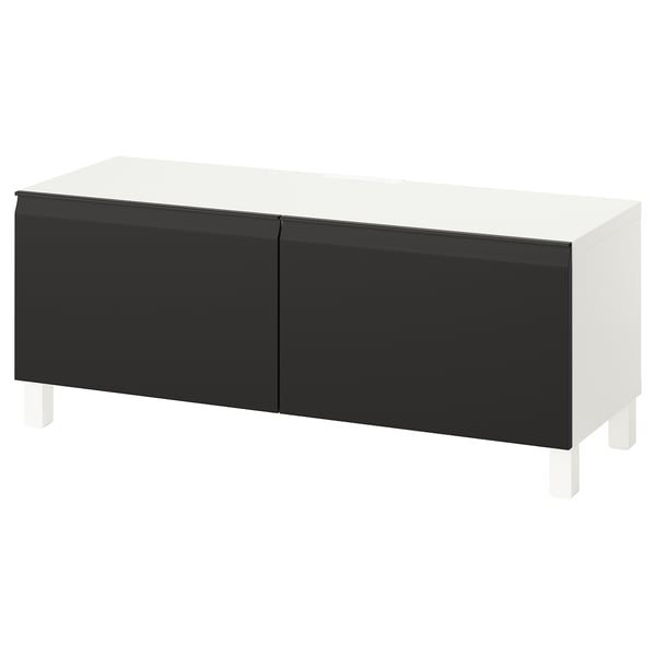 Un banc TV BESTÅ blanc et noir au design épuré et minimaliste et doté d’étagères réglables pour le rangement.