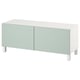 Meuble TV blanc moderne avec 2 portes vert pastel, design minimaliste, pieds en bois.