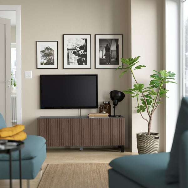 Salon moderne avec meuble TV BESTÅ, télévision à écran plat, armoire de rangement et plante. Canapés bleu-vert avec oreiller jaune.