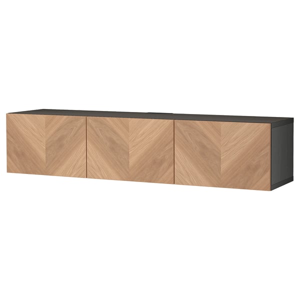 Le banc TV BESTÅ en bois brun clair et noir, rectangulaire avec trois portes battantes, conçu pour le rangement et la gestion des câbles.