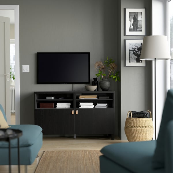 Salon moderne avec banc de télévision noir BESTÅ, design élégant, grand espace de rangement, télévision à écran plat, objets de décoration et sièges bleu sarcelle.