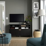 Salon moderne avec banc de télévision noir BESTÅ, design élégant, grand espace de rangement, télévision à écran plat, objets de décoration et sièges bleu sarcelle.
