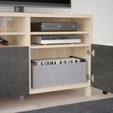 Meuble TV en bois avec étagères réglables, abritant une console de jeux, un appareil de streaming et des jeux organisés. Gestion des câbles arrière.