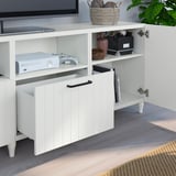 Banc TV BESTÅ blanc avec étagères réglables, contenant une console de jeu, des commandes et un rangement organisé.