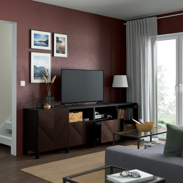 Salon moderne aux murs marron, doté d’un banc TV BESTÅ avec rangement organisé et étagères réglables pour les câbles.