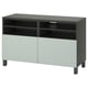 Un banc TV ikea BESTÅ en vert avec des portes gris clair, doté d’étagères ouvertes et de compartiments réglables avec gestion des câbles.