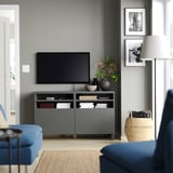 Salon moderne avec meuble TV gris BESTÅ, canapé bleu, lampe et art mural.