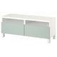 Meuble TV blanc moderne avec tiroirs vert clair, design élégant, contient des appareils électroniques, organise les accessoires.
