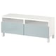 Meuble TV blanc et gris, design minimaliste avec 2 tiroirs, compartiments ouverts et pieds en métal.