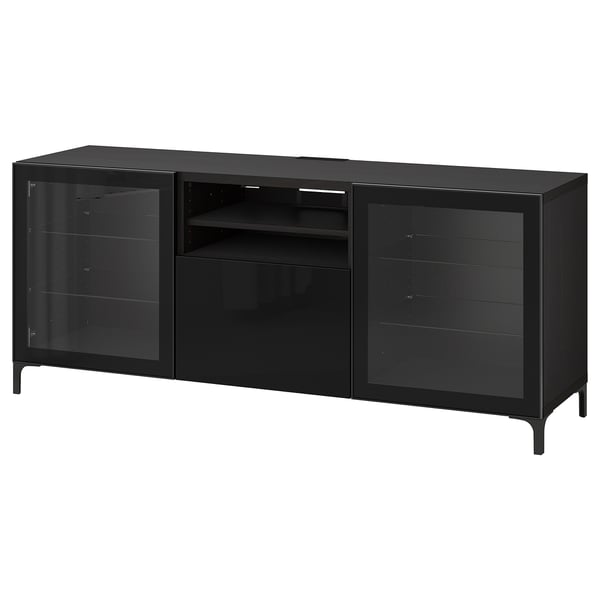 Un banc tv ikea BESTÅ noir avec des portes en verre. Il s’agit d’un design moderne et élégant avec des pieds en métal et idéal pour le stockage et la gestion des câbles.