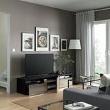 Salon moderne avec banc TV BESTÅ, deux tiroirs et lampadaire à côté de la fenêtre.