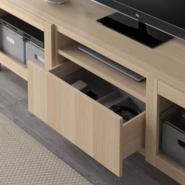 Meuble tv en bois clair avec tiroir ouvert affichant les articles stockés. Conçu pour la gestion et l’organisation des câbles.