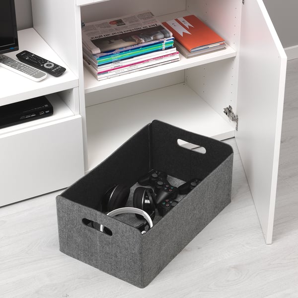 Étagère blanche avec boîte de rangement, contenant des manettes de jeu et des écouteurs. La boîte est conçue pour un rangement organisé et un accès facile.