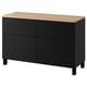 Un buffet BESTÅ noir et bois avec quatre compartiments et des pieds noirs. Il s’agit d’un design élégant et moderne pour le rangement.