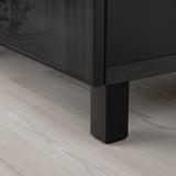Une unité de rangement noire moderne sur un plancher en bois clair, présentant une construction robuste et un design élégant.