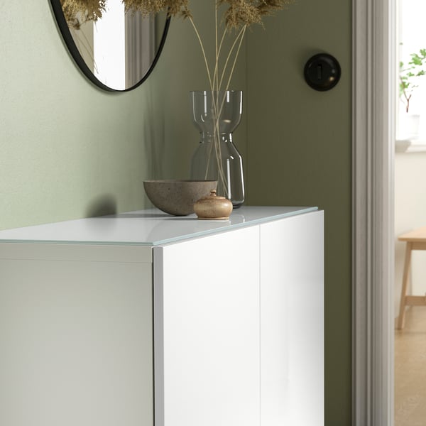 Panneau supérieur en verre blanc BESTÅ, élégant et minimaliste, s’adapte à plusieurs unités, petites plantes séchées et bol sur le dessus.