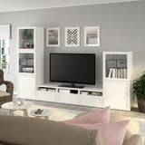 Salon moderne avec télévision à écran plat sur BESTÅ, armoires en verre, chaise en osier, tapis gris.
