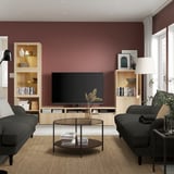 Salon moderne avec des murs marron, des canapés gris, une table basse en verre, des étagères en bois et une télévision sur console multimédia avec gestion des câbles.