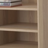 Étagère en bois avec trois étagères vides et une pile de livres sur le dessus. Les étagères sont réglables.