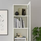 Étagère BILLY blanche avec des vases, des livres et des objets décoratifs sur l’étagère inférieure, un côté a des portes en verre.