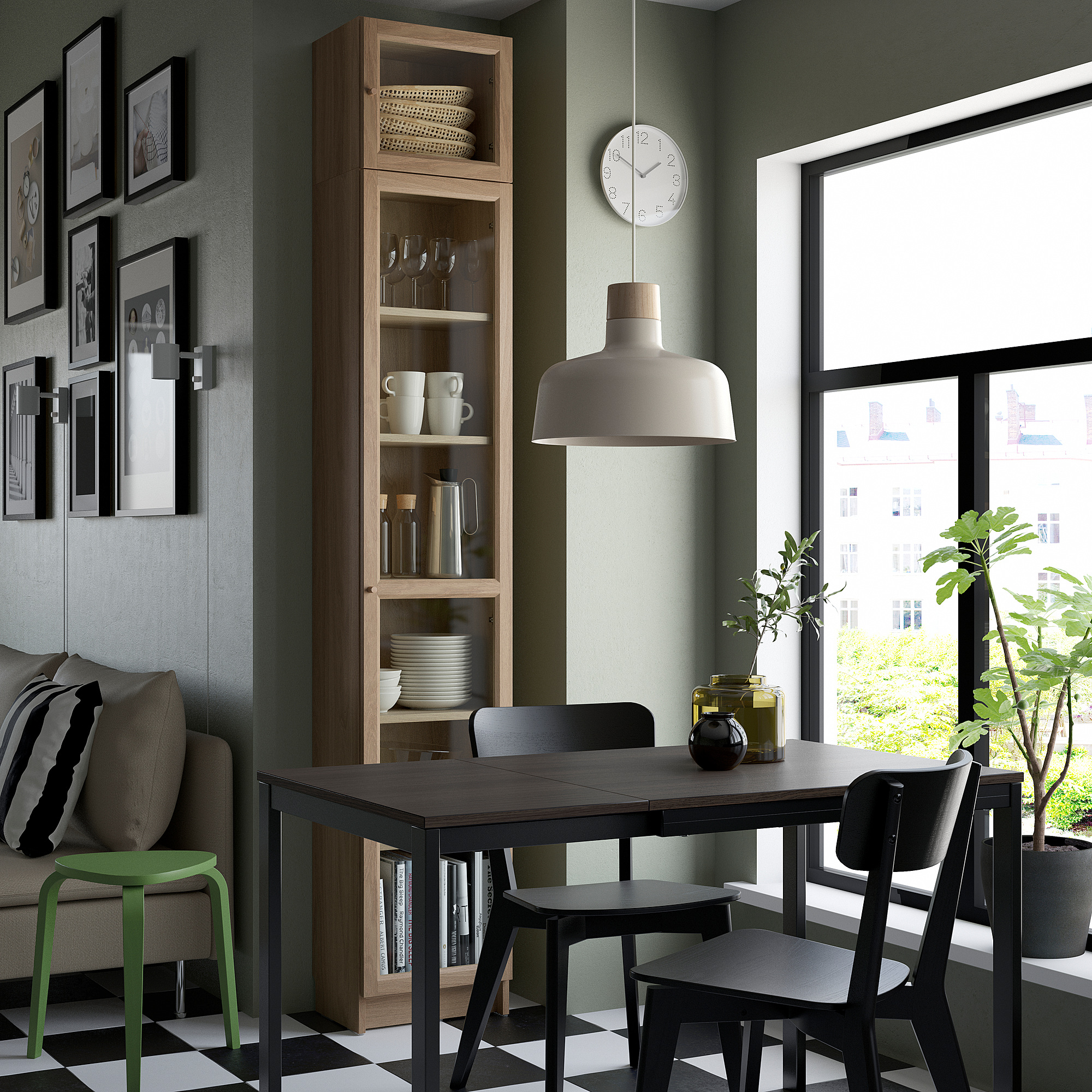 Salle à manger moderne avec grand rangement en bois BILLARD, mur vert, chaises noires, table, lampe signature, mur de galerie d’art, grande fenêtre et plantes.