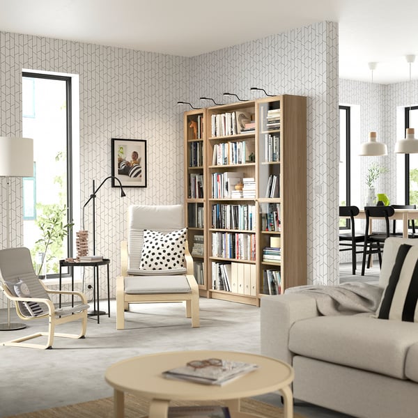 Salon moderne avec bibliothèque, canapé, fauteuils et lampe.