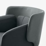 Gros plan d’un fauteuil moderne rembourré, présentant un tissu élégant et un design incurvé pour le confort et le style.