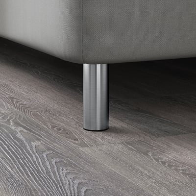 Gros plan sur les pieds de meubles modernes, montrant un support robuste en acier inoxydable sur un plancher en bois foncé.