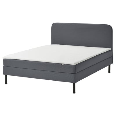 Lit divan moderne gris avec tête de lit rembourrée et matelas blanc.