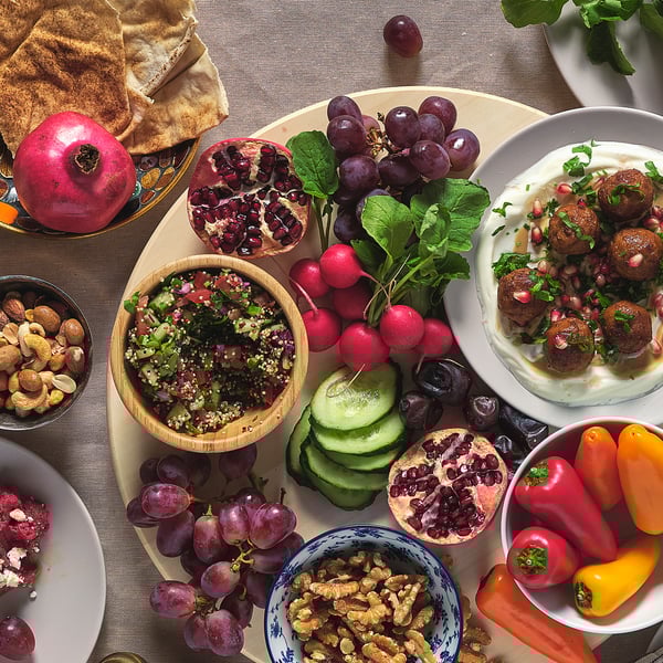 Assortiment de fruits, de noix et de plats sur des bols de service en bois, en métal et en verre, mettant en valeur leur empilabilité et leur utilisation polyvalente.