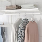 Armoire blanche avec système BOAXEL : suspendre les vêtements et les serviettes pliées sur des étagères.
