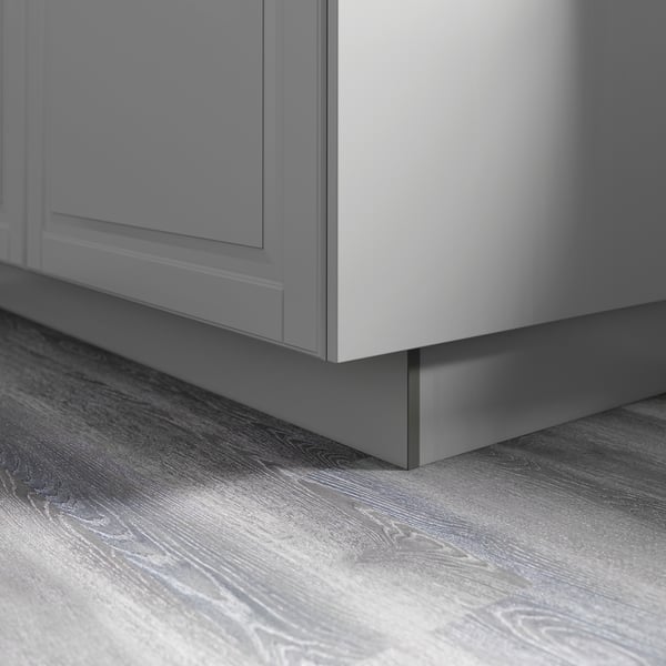 Armoire de cuisine grise avec finition laquée lisse, fixée au sol en bois avec grain visible, démontrant un style minimaliste et une surface facile à nettoyer.