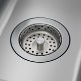 Drain d’évier en acier inoxydable avec bouchon central, poli jusqu’à ce qu’il brille, reflétant la propreté et la qualité durable.