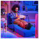 L’homme est allongé dans une chaise longue bleue BRÄNNBOLL, lisant, les pieds en l’air, à côté de pop-corn.
