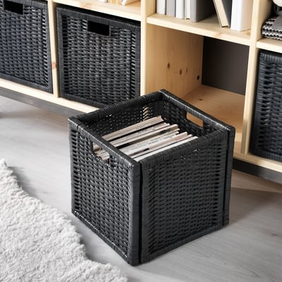 Paniers tressés noirs sur une étagère en bois, contenant des magazines et des livres. Poignées pour un levage facile.