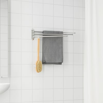 Porte-serviettes argenté BROGRUND avec serviettes grises et brosse en bois, monté sur mur carrelé blanc, petite taille.