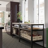Étagère de rangement en métal noir avec caisses en bois et articles de cuisine près de la fenêtre.