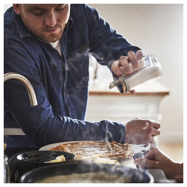L’homme secoue le sucre de CITRONHAJ, récipient transparent, couvercle en acier inoxydable, sur les aliments.