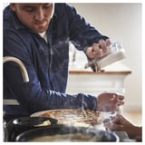 L’homme secoue le sucre de CITRONHAJ, récipient transparent, couvercle en acier inoxydable, sur les aliments.
