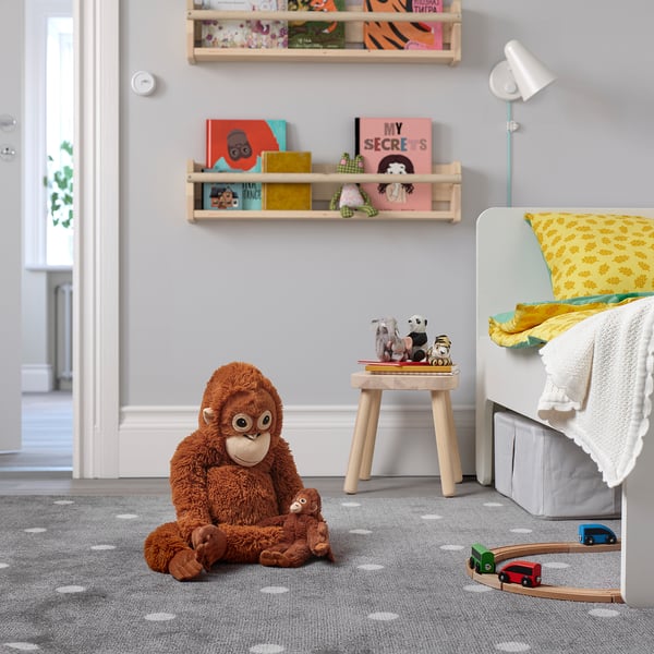 Chambre d’enfant avec grand jouet singe DJUNGELSKOG, étagères, tabouret avec des animaux en peluche, berceau et train jouet.